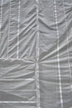 Close-up of durable industrial tarpaulin fabric stretched taut in a factory setting with muted lighting.