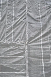 A large roll of clear plastic sheeting being unrolled on a construction site.