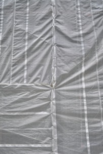 A large roll of durable construction tarp spread out on the ground.