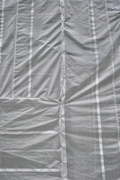 A large roll of clear plastic sheeting being unrolled on a construction site.