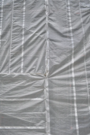 Close-up of durable industrial tarpaulin fabric stretched taut in a factory setting with muted lighting.