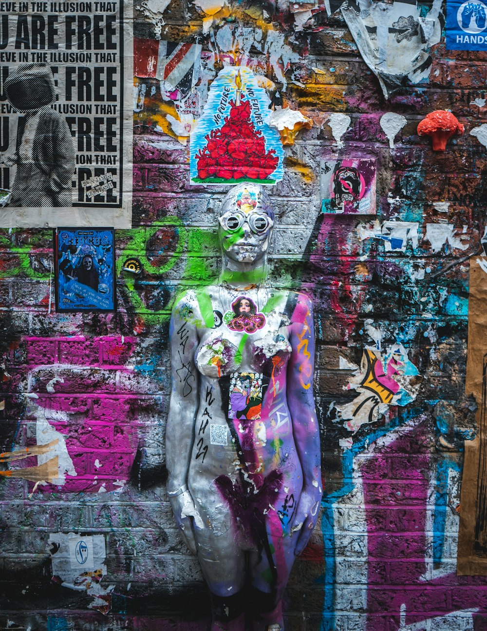 Frau in grauer Jacke und lila Hose neben Graffiti-Wand