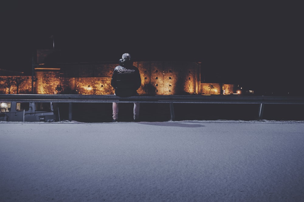 man in black jacket sitting on bench during night time