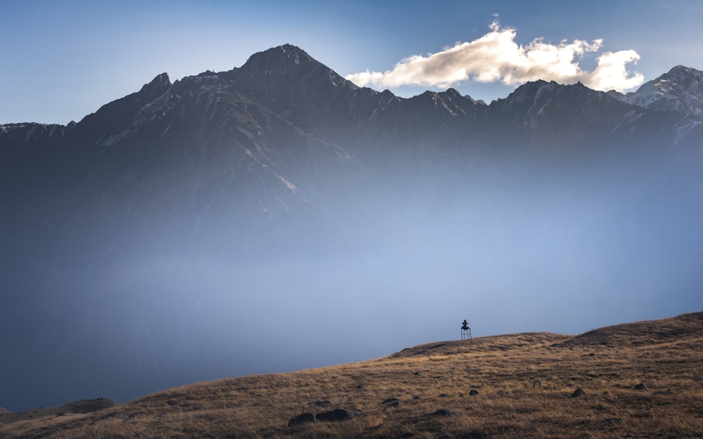 person standing on brown grass field near snow covered mountain during daytime