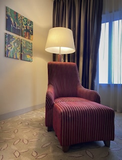 A cozy corner of a deluxe room showcasing tasteful artwork and a plush armchair beside a floor lamp.