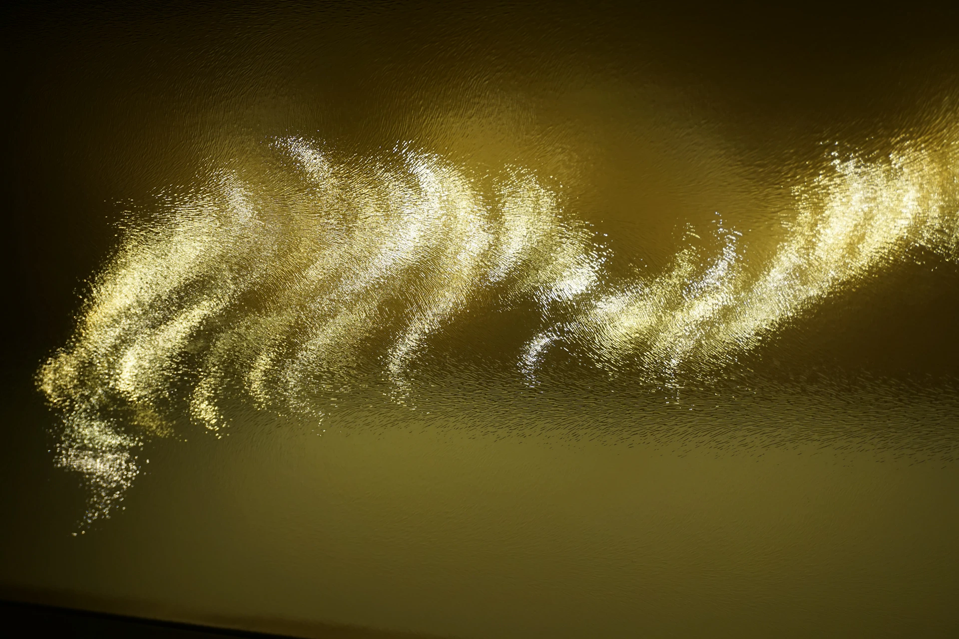 A close-up shot of a glowing ripple effect spreading across a smooth button, capturing the light hues of gold and amber.