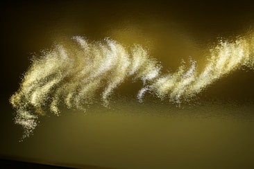 Glowing, wavy patterns of light gently ripple across a textured, reflective surface. The golden hues are interspersed with shimmering highlights, creating an abstract and ethereal appearance.