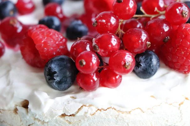 Close-up of a beautifully decorated pavlova topped with fresh berries and mint leaves.