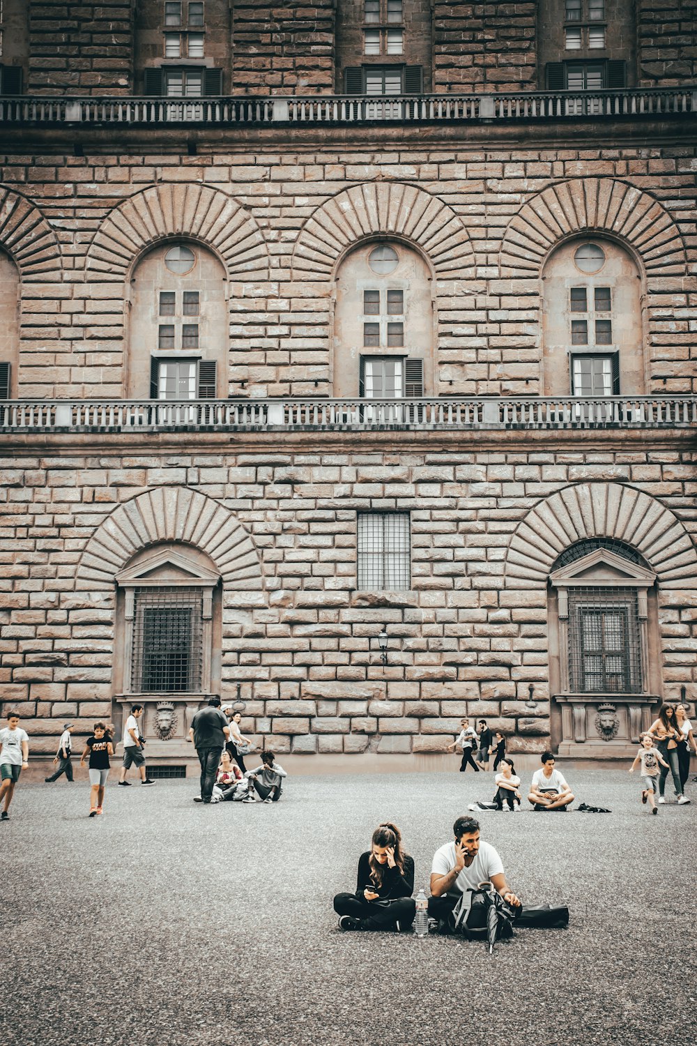 people sitting on bench near brown brick building during daytime