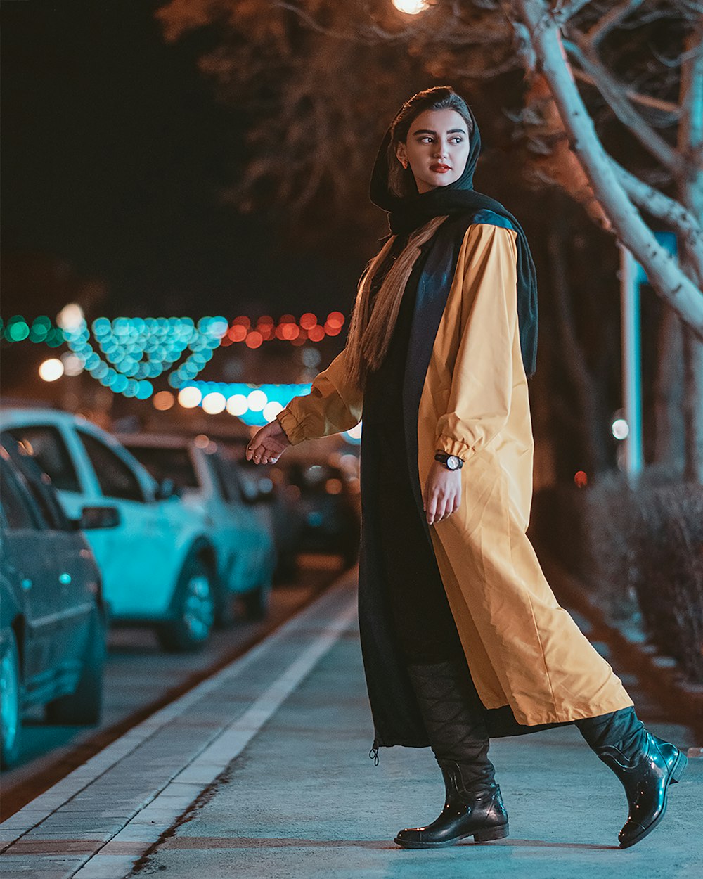 woman in brown coat standing on sidewalk during daytime