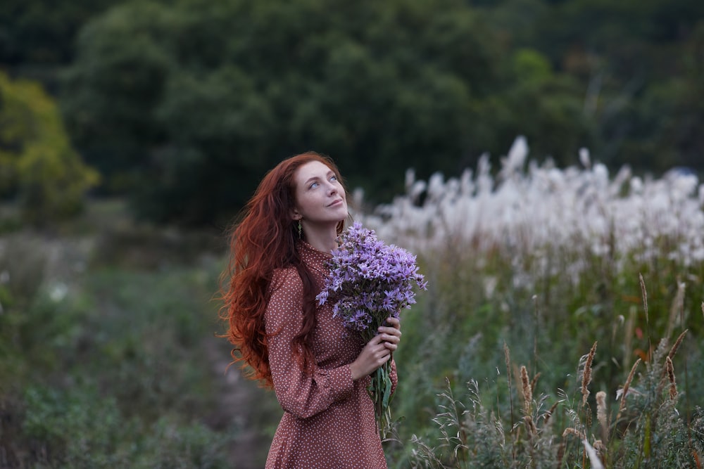 Femme en pull marron tenant des fleurs violettes