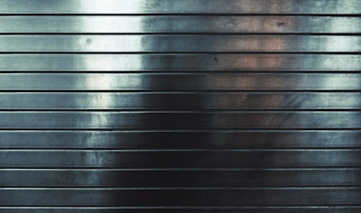 Metallic surface with horizontal grooves, reflecting subtle gradients of light and shadows.