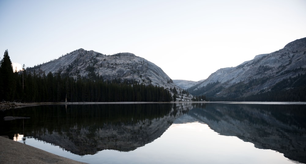 lake near mountain under white sky during daytime