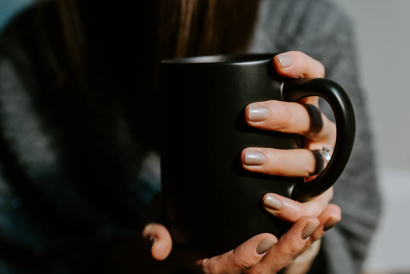 Hands holding a black ceramic mug