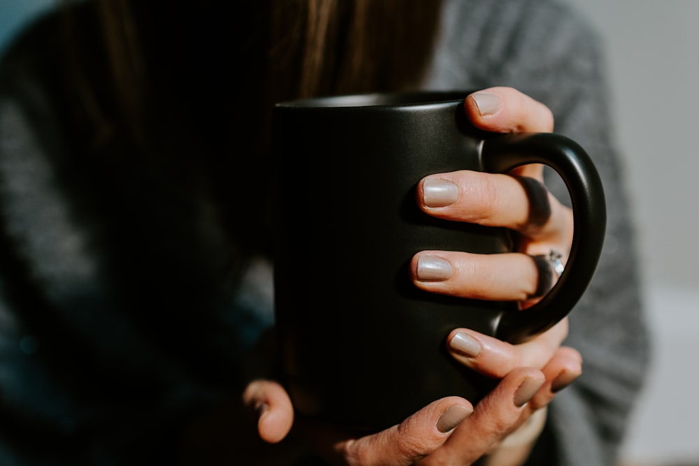 person holding black ceramic mug