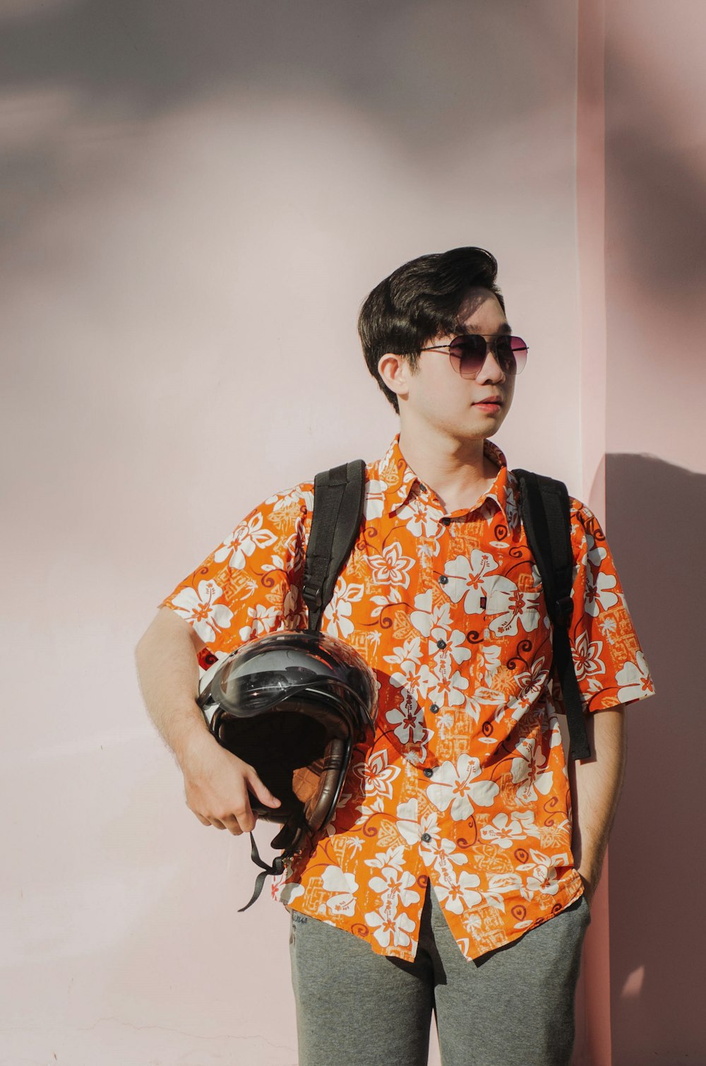 Chico con camiseta abotonada floral naranja y amarilla con auriculares negros