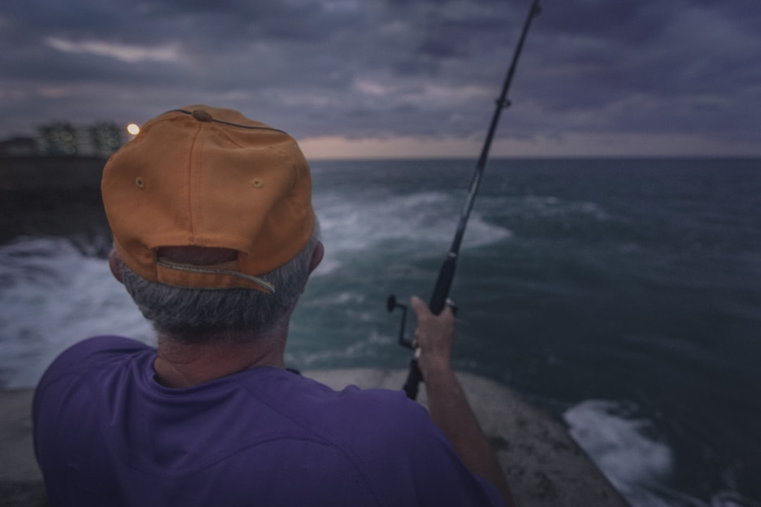 man in blue crew neck shirt holding black fishing rod