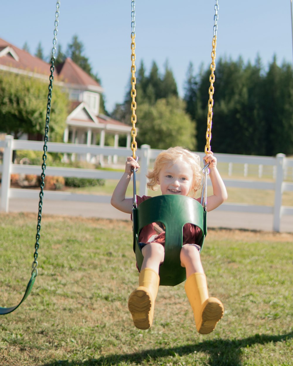 girl in blue shirt and black shorts sitting on swing during daytime