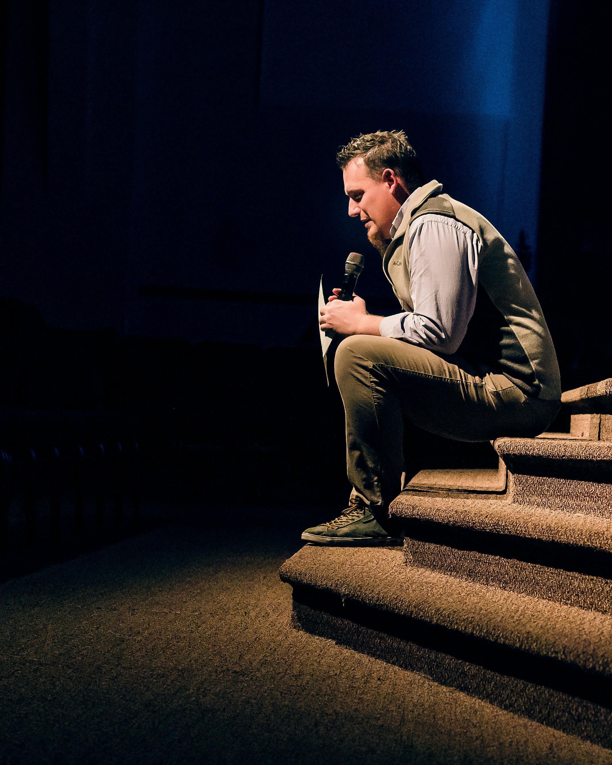 man in gray dress shirt and gray pants sitting on brown staircase