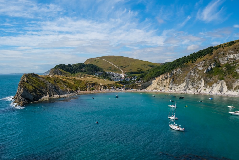 white boat on sea near green mountain under blue sky during daytime