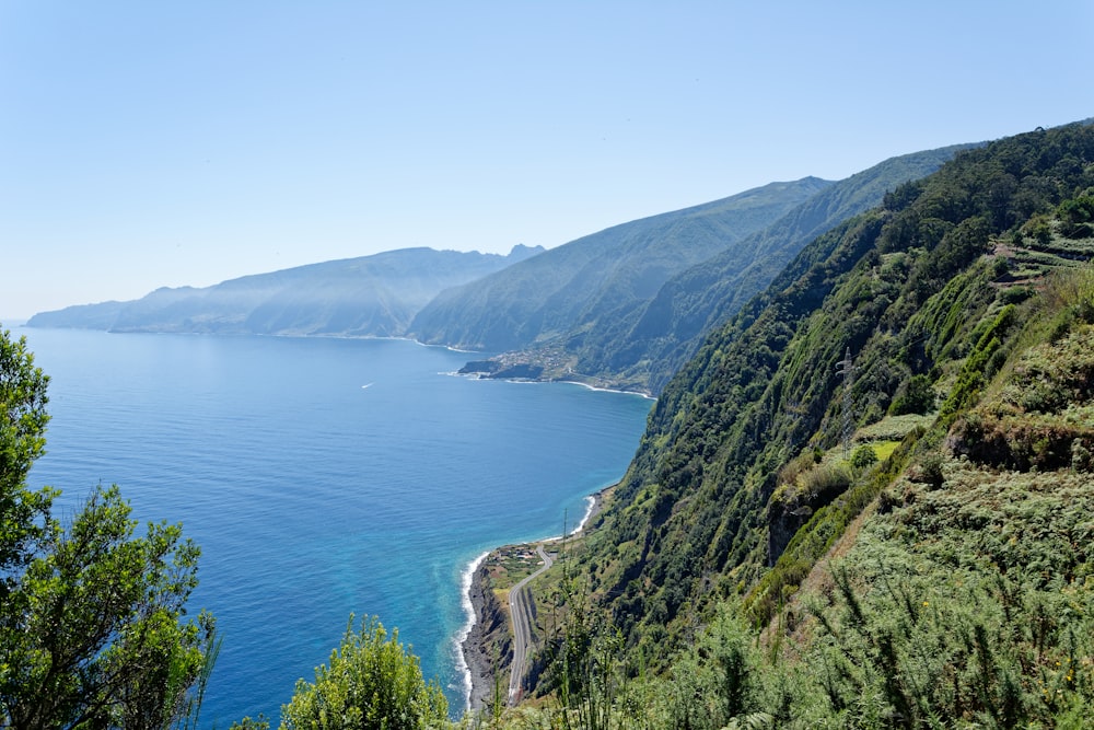 montagna verde accanto allo specchio d'acqua durante il giorno