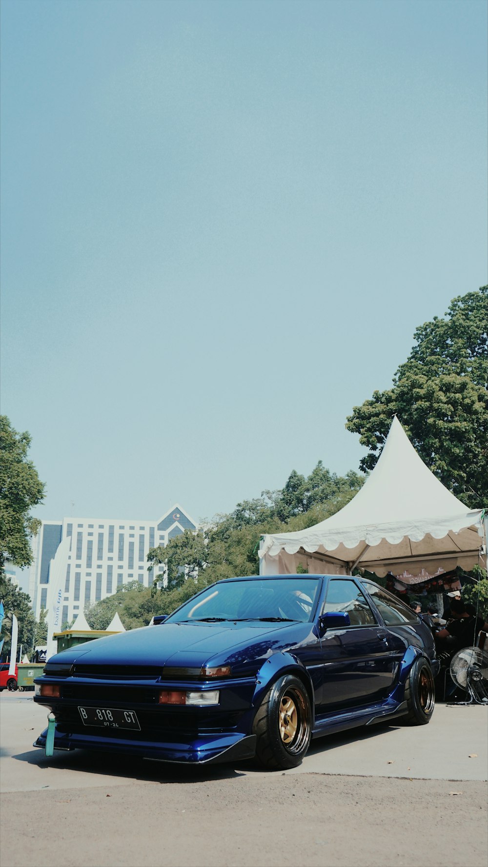 낮 동안 흰색과 갈색 건물 근처에 주차된 파란색 컨버터블 자동차