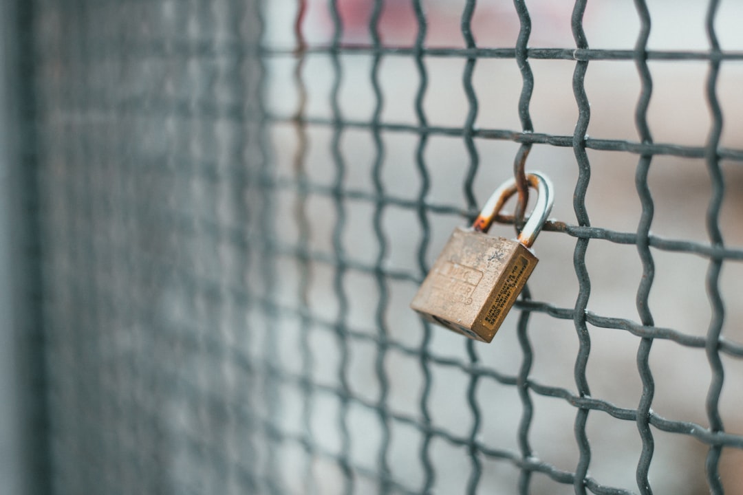 brown padlock on black metal fence