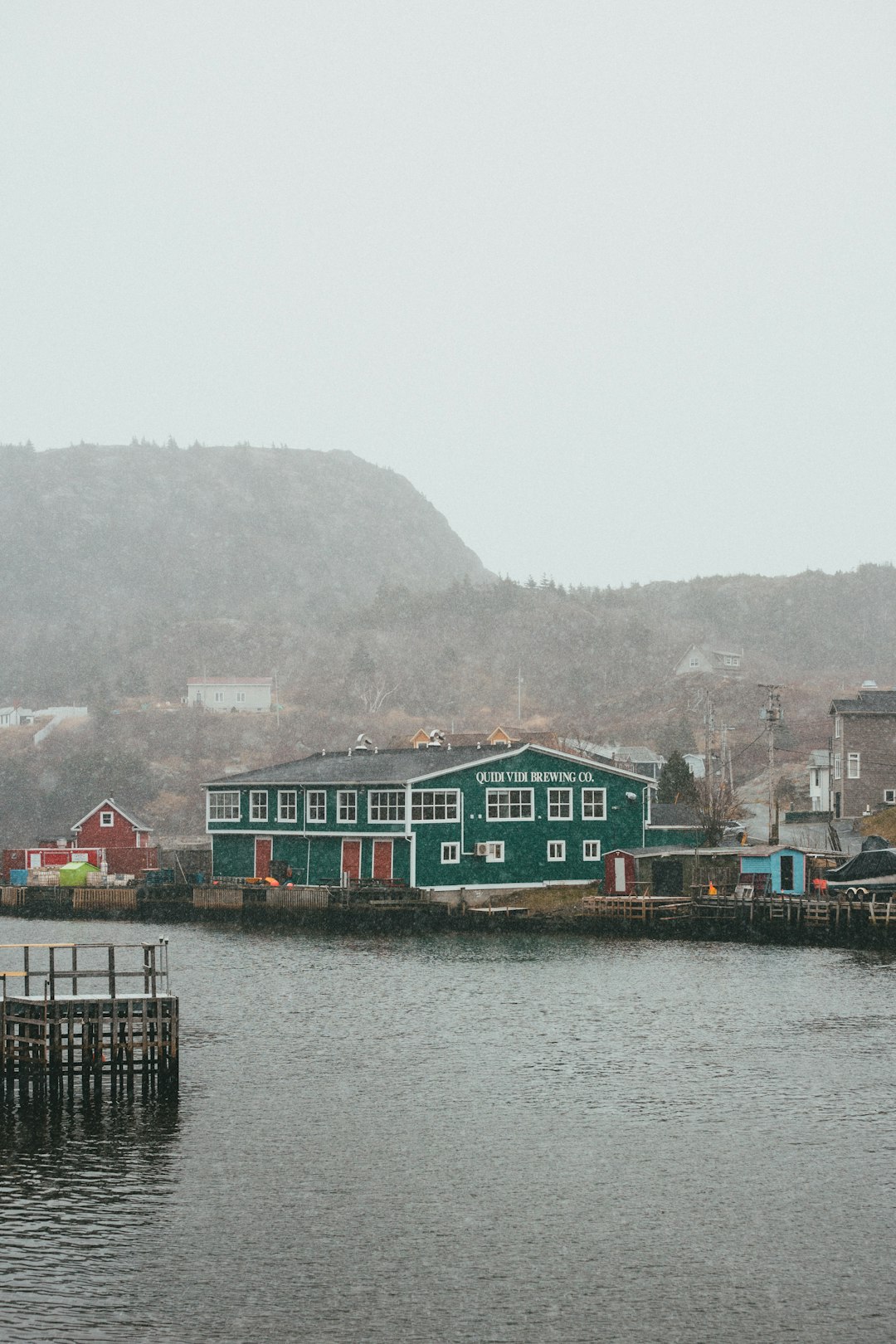 green and brown wooden houses beside body of water during daytime