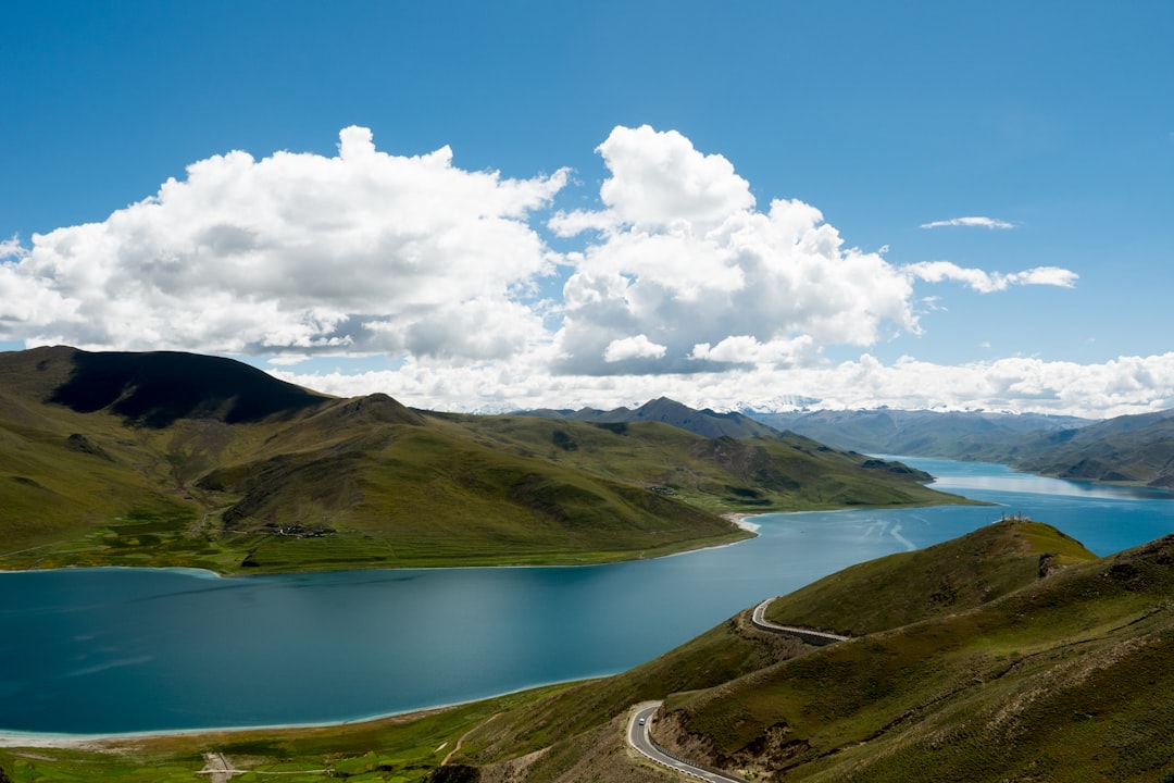 green mountains beside lake under blue sky and white clouds during daytime