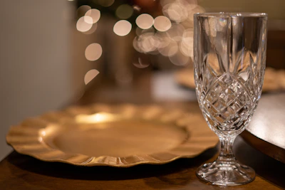 A close-up of a polished copper dinner plate reflecting warm light on a rustic wooden table.