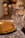 An elegant crystal glass with intricate patterns stands on a table, alongside a gold plate. Soft bokeh lights create a warm, festive ambiance in the background, enhancing the luxurious setting.