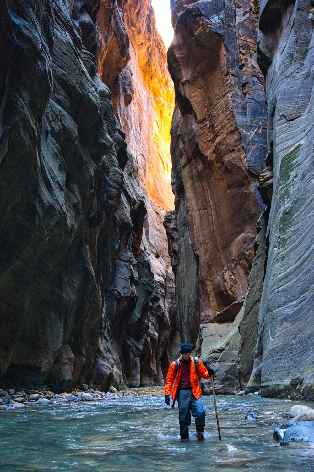 a man walking through a narrow river in a canyon