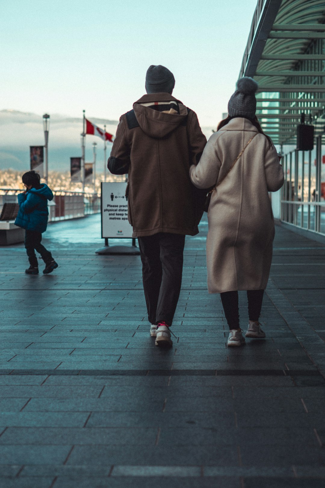 man in brown coat walking on sidewalk during daytime