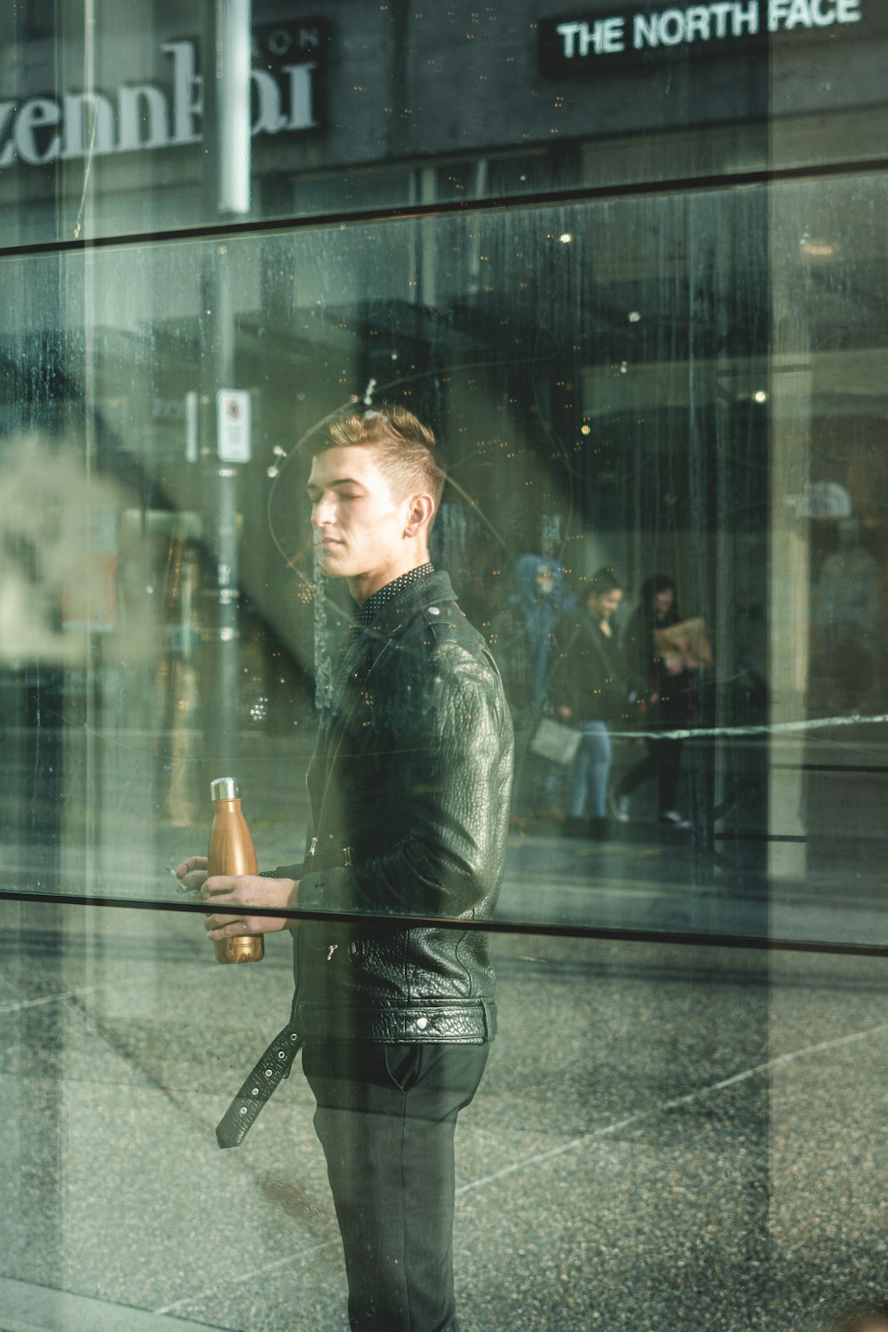 woman in black leather jacket standing in front of glass wall