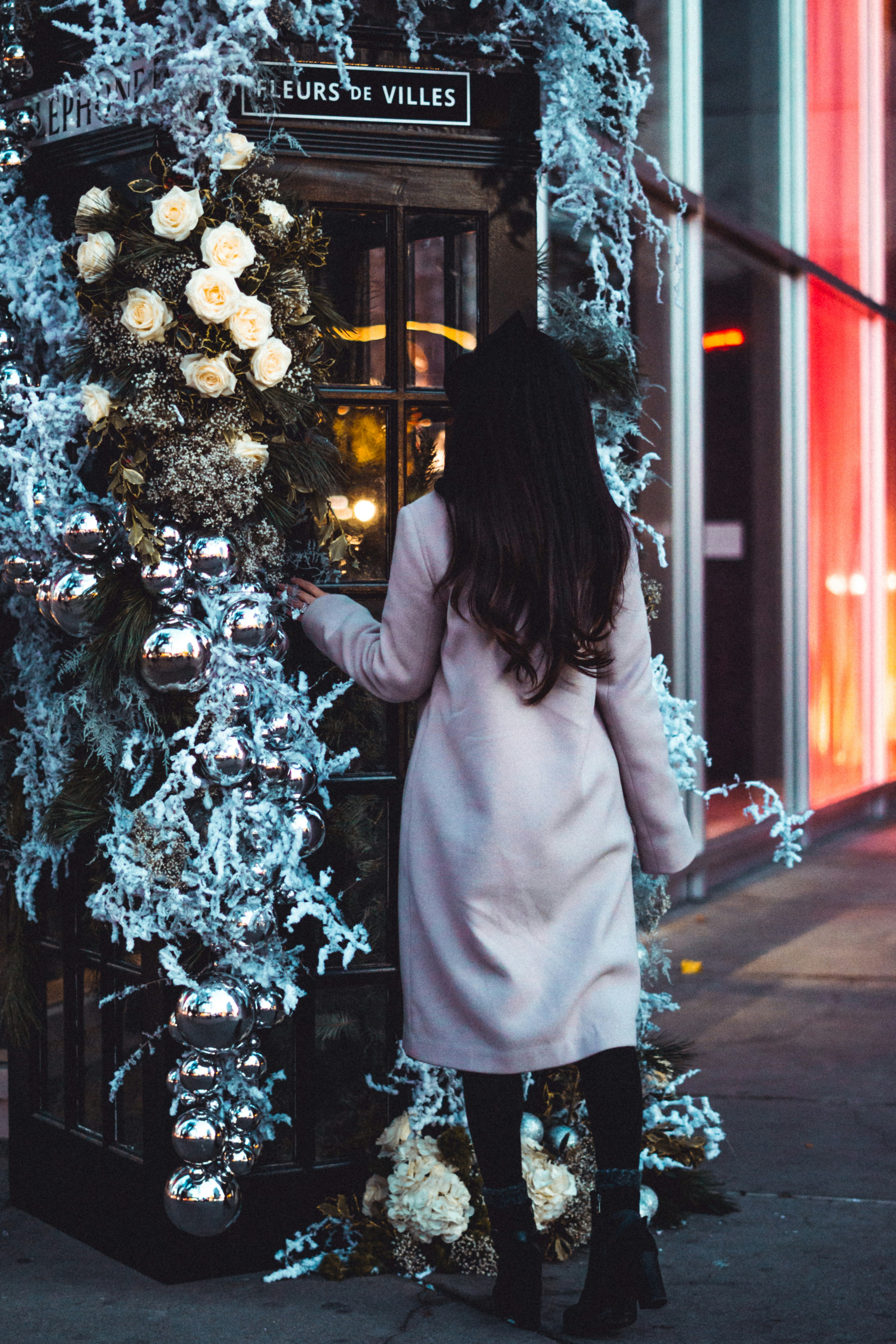 woman in pink coat standing beside christmas tree