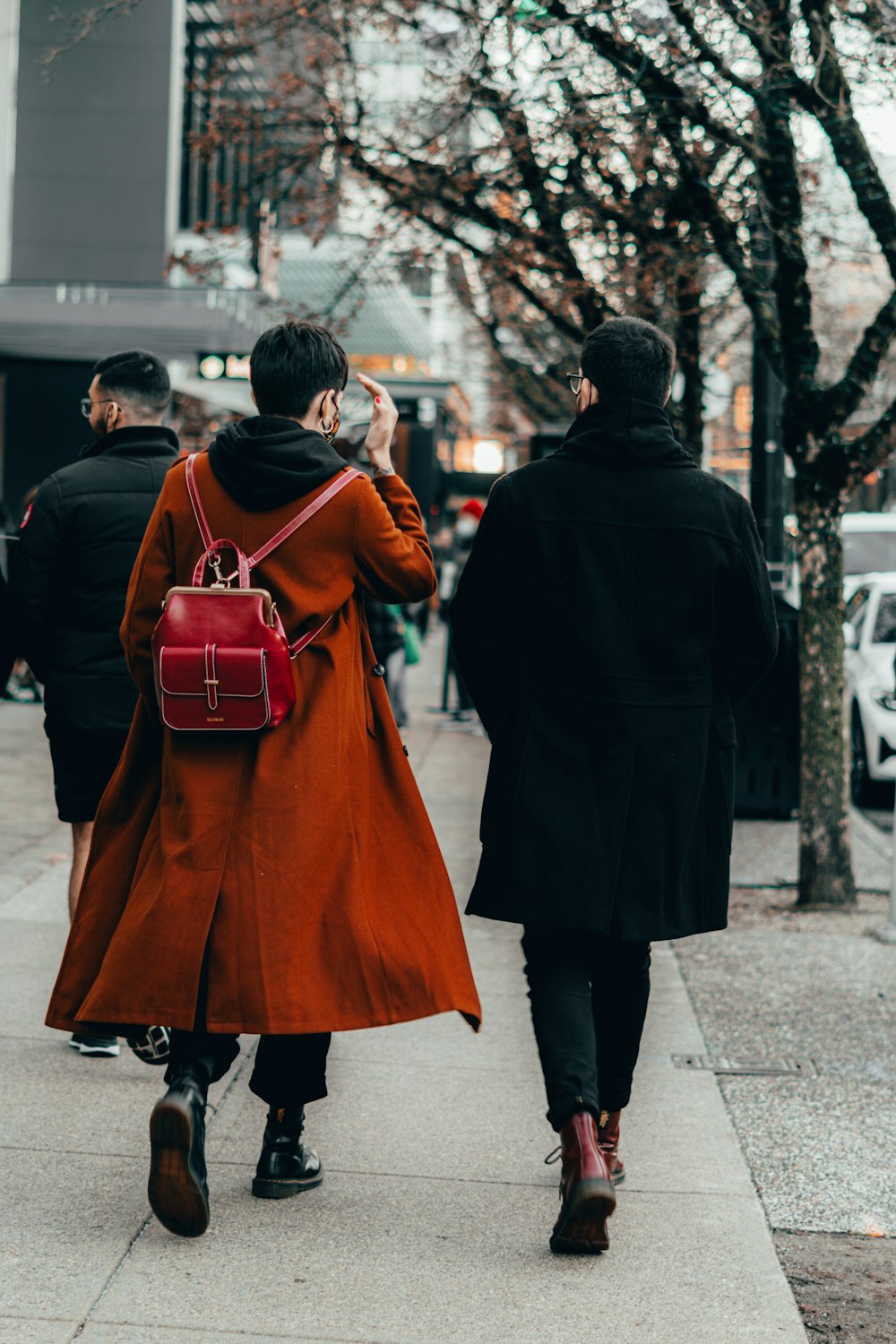 man in black coat walking on sidewalk during daytime