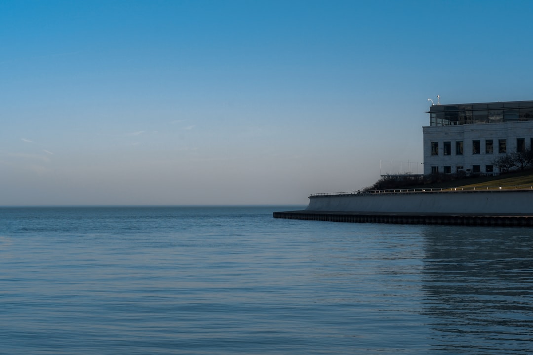 white and black lighthouse on sea under blue sky during daytime