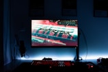 A gaming setup features a glowing monitor displaying a futuristic cityscape with the word 'Cyberpunk' prominently featured on the screen. The setup includes a backlit keyboard and a computer mouse, with a microphone and headphones to the side. The ambiance is dark with illuminated accents.