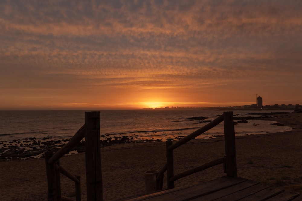 clôture en bois marron sur la plage au coucher du soleil