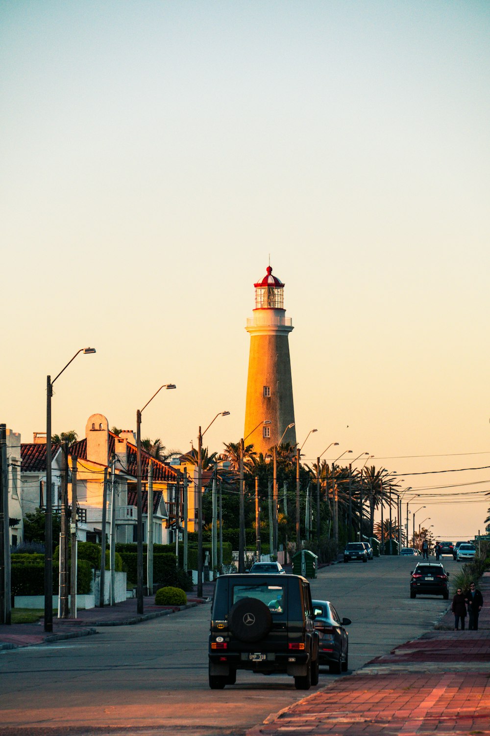 white and brown concrete lighthouse near green palm trees during daytime