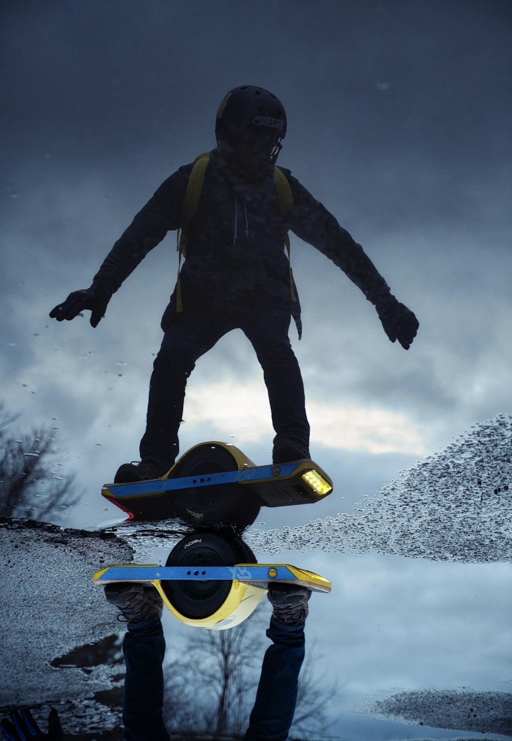 homme en veste noire et jean bleu en jean surfant sur un snowboard bleu et jaune pendant la journée