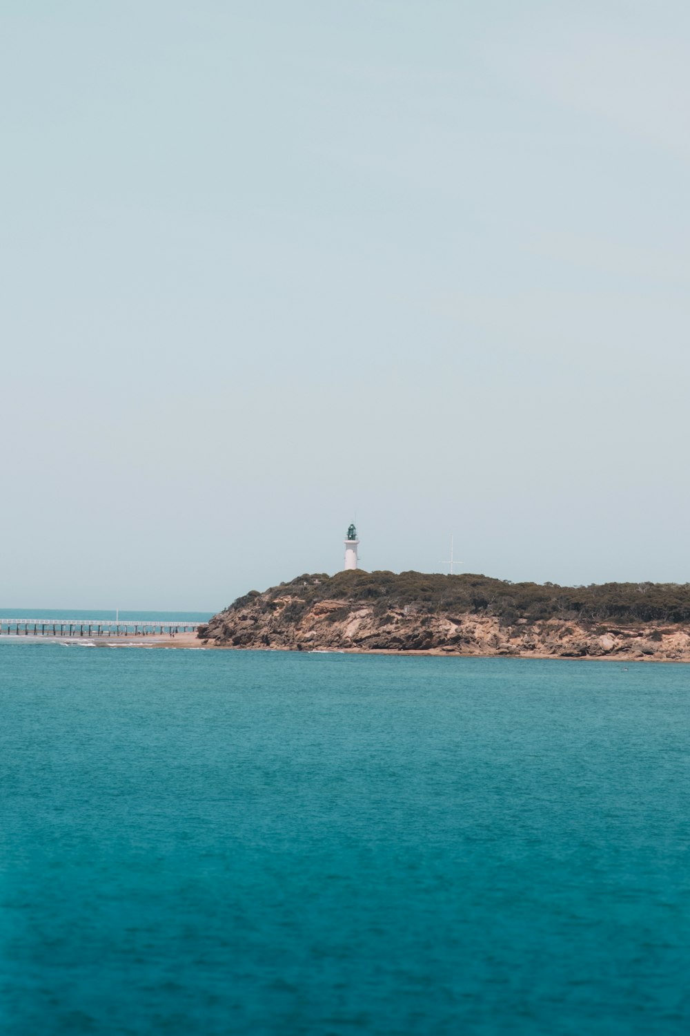 person standing on rock formation in the middle of sea during daytime