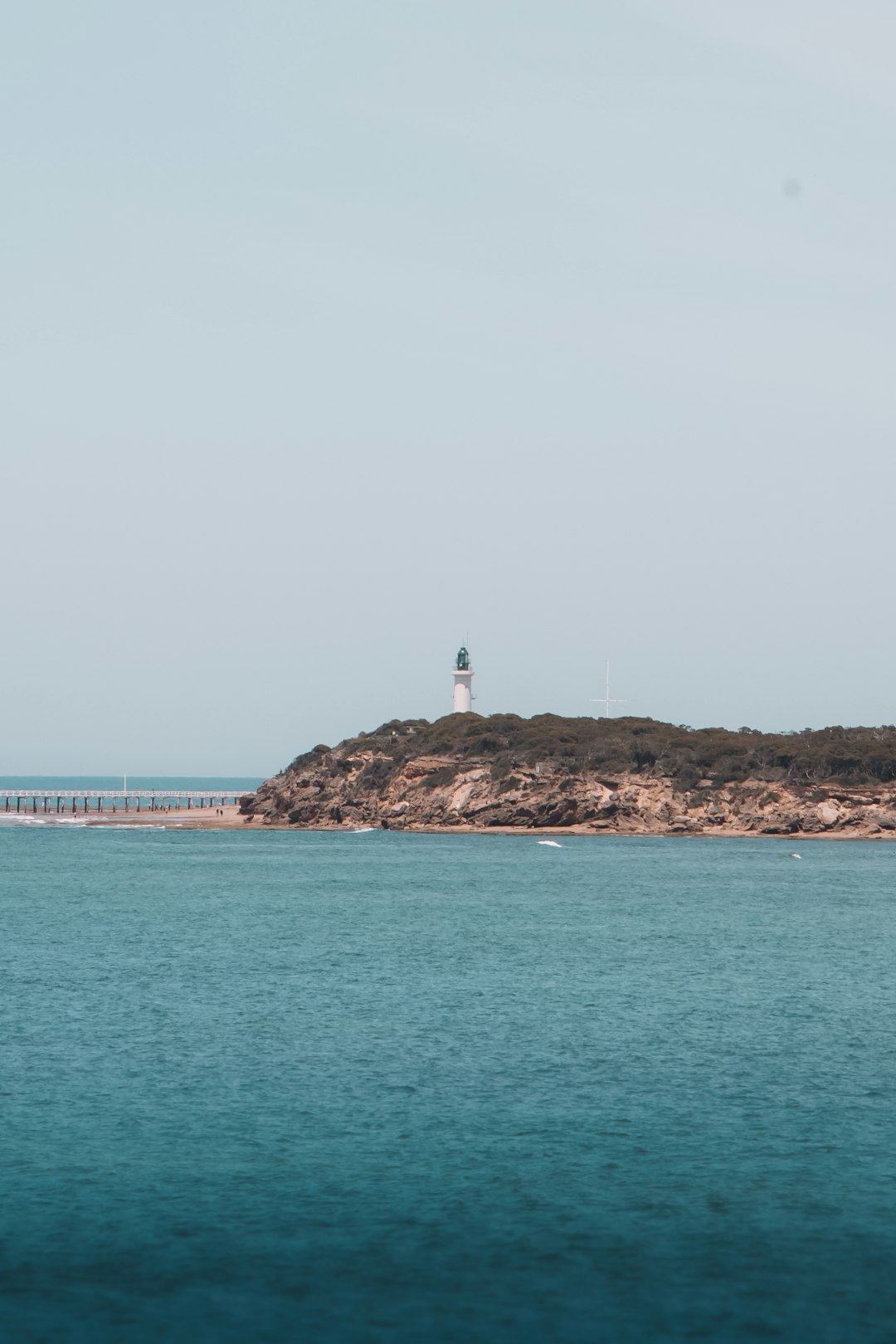 white lighthouse on brown rock formation near sea during daytime