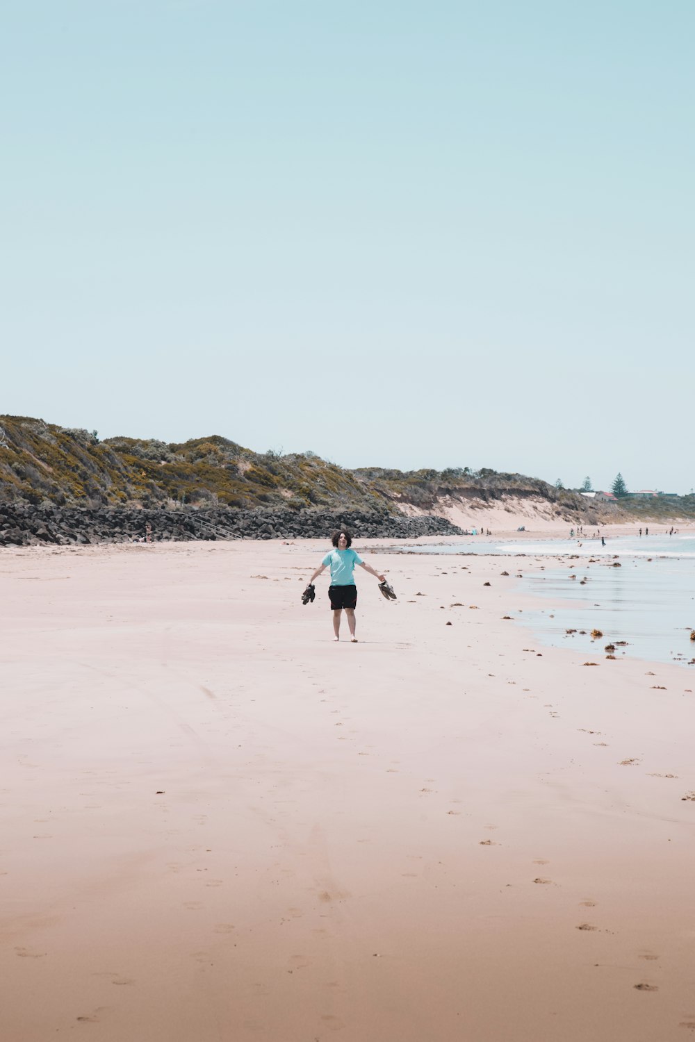 person in blue jacket walking on beach during daytime