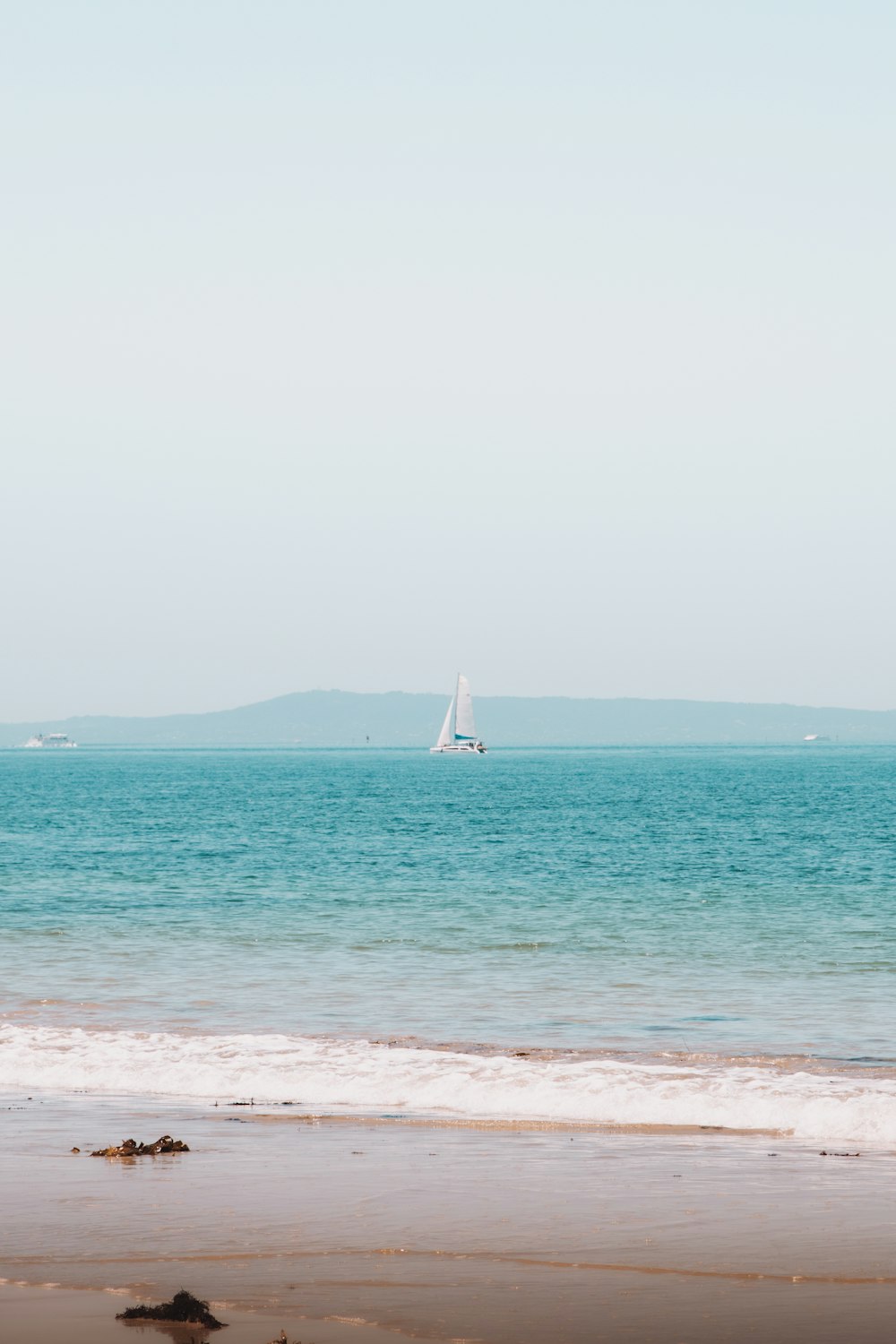 white sailboat on sea under white sky during daytime