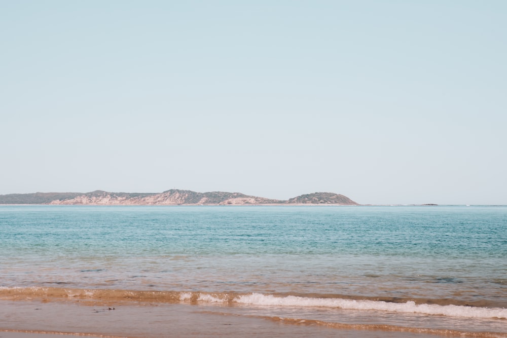 body of water near mountain during daytime