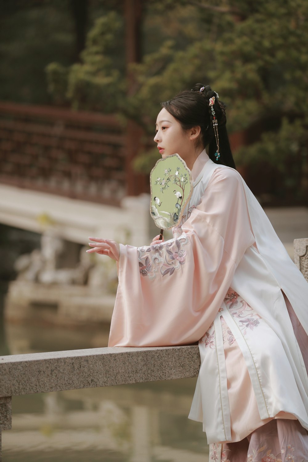 woman in pink and white dress sitting on gray concrete bench during daytime