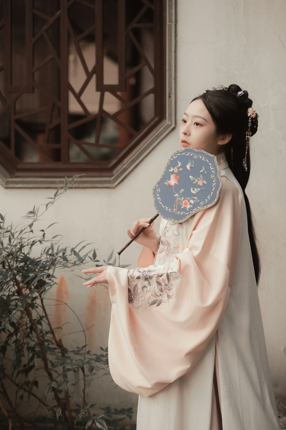 woman in pink long sleeve dress holding blue and white floral hand fan