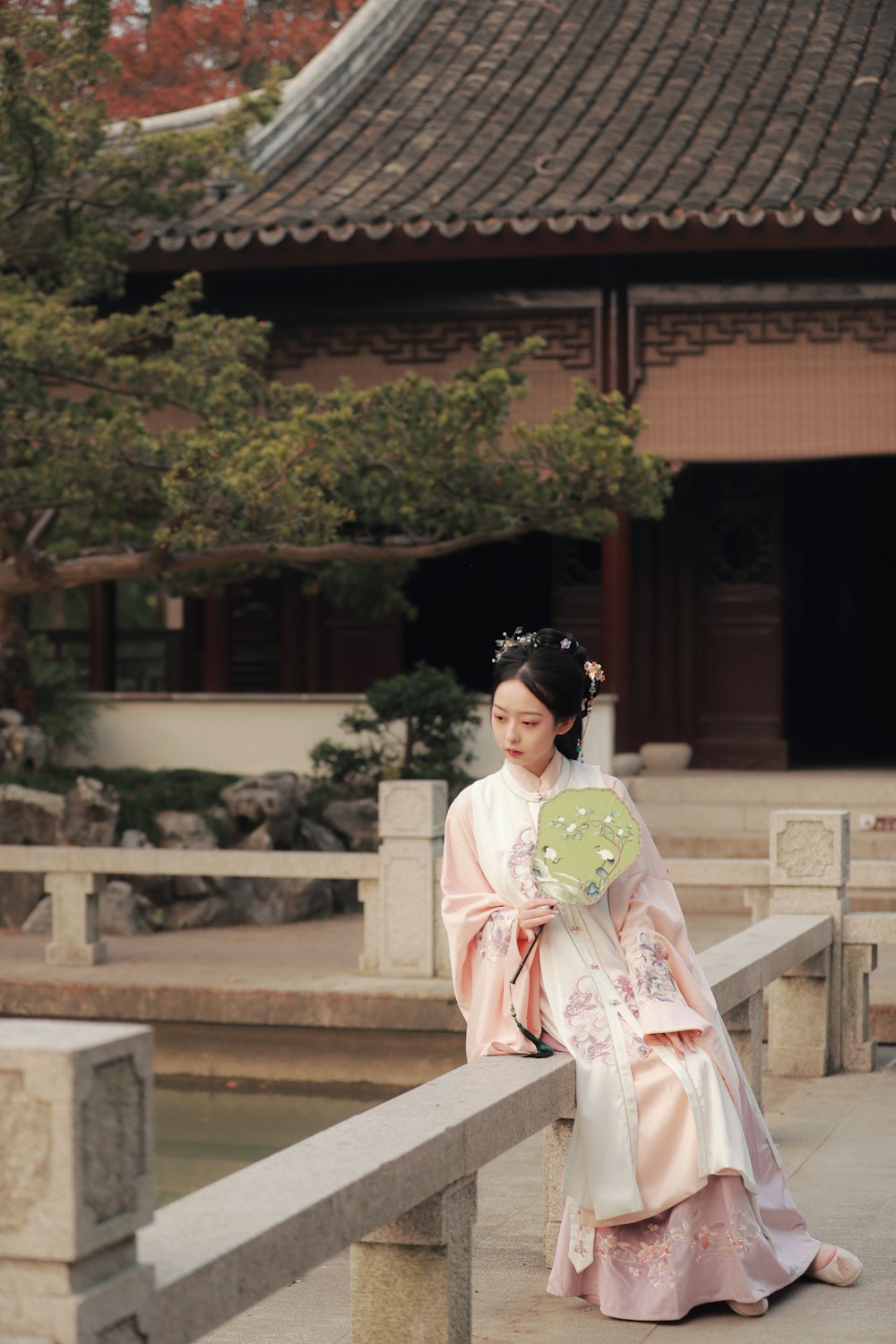 woman in white and pink floral kimono sitting on brown concrete bench