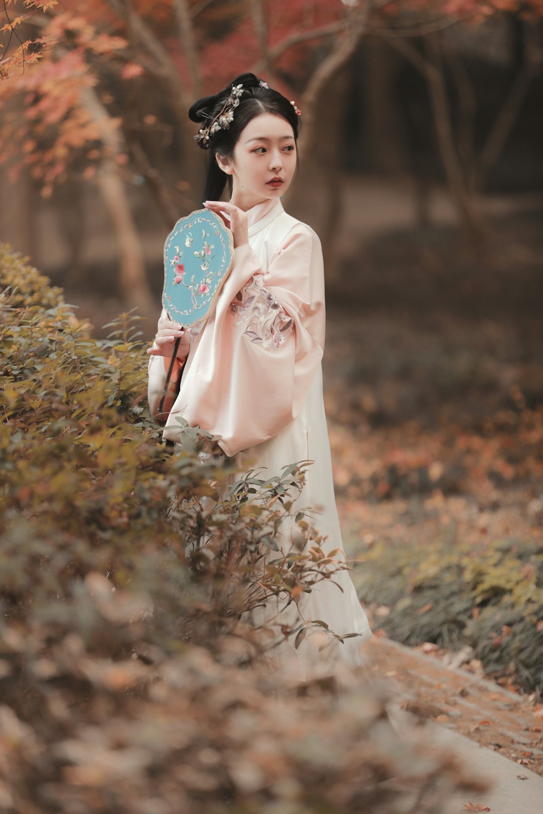 woman in white and pink long sleeve dress standing on brown dried leaves during daytime